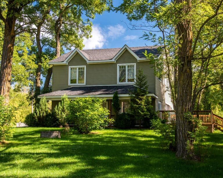 Two story home nestled between two green trees